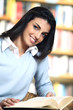 smiling female student with book in hands in a bookstore