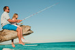 Fishing team - little girl fishing with father at the beach