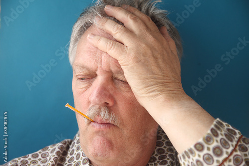 Photo: senior man with a fever and aching head senior man with a fever and aching head