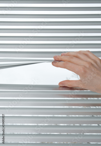 Photo: Hand opening venetian blinds for peeking Hand opening venetian blinds for peeking