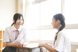 教室で会話している2人の女子中学生