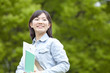 新緑の下で微笑む大学生
