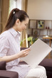 ソファーに座りばがら雑誌を読む女性
