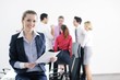 Photo: business woman standing with her staff in background business woman standing with her staff in background