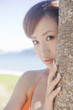 椰子の木から顔を覗かせる水着女性