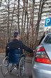 Mann im Rollstuhl neben Auto