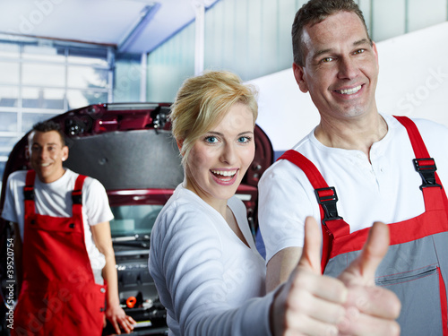Foto: Motor mechanics and customer in garage show thumbs up Motor mechanics and customer in garage show thumbs up