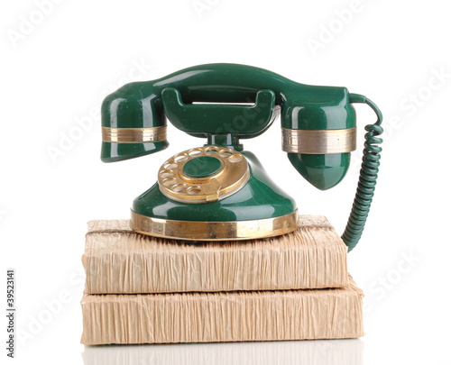 Photo: Retro phone standing on books isolated on white Retro phone standing on books isolated on white