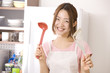 おたまとフライ返しを持って微笑む女性