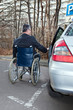 Mann im Rollstuhl neben Auto