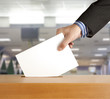 Hand putting a voting ballot in a slot of box