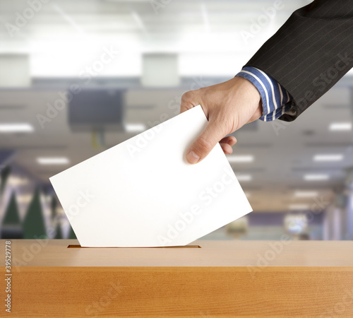 Photo: Hand putting a voting ballot in a slot of box Hand putting a voting ballot in a slot of box
