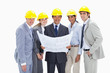 Close-up of smiling business people wearing safety helmets holding construction plans