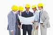 Business people wearing safety helmets watching construction plans