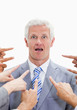 Close-up of shocked businessman with fingers being pointed at him