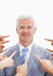 Smiling businessman with fingers being pointed at him