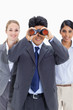 Smiling businessman looking through binoculars with two girls behind him