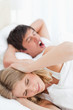 Photo: The man's snoring is so bad that the woman is blocking her ears and very annoyed The man's snoring is so bad that the woman is blocking her ears and very annoyed