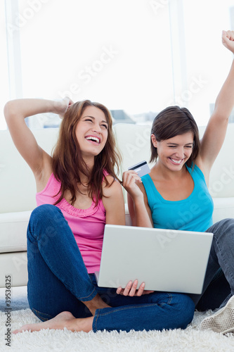 Photo: Successful young women holding a credit card and a laptop Successful young women holding a credit card and a laptop