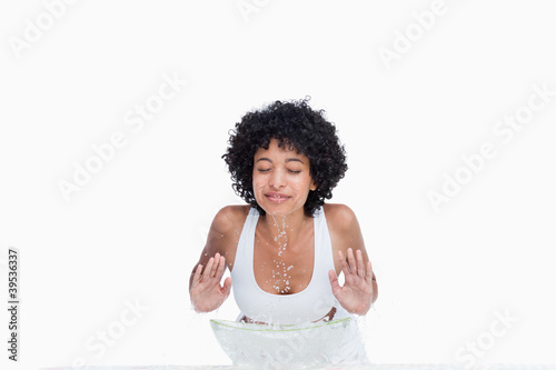 Photo: Young relaxed woman washing her face with water behind a bowl Young relaxed woman washing her face with water behind a bowl