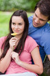 Young woman smelling a flower while being accompanied by her boyfriend