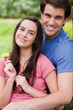 Young happy couple standing upright in a public garden with a flower