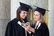 Young smiling graduating student photographing herself and a friend