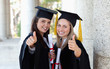 Smiling graduating students putting their thumbs up
