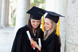 Photo: Smiling graduating students looking at a digital camera while standing upright Smiling graduating students looking at a digital camera while standing upright