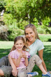 A smiling mother and her daughter lying together on the grass