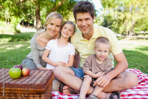 Photo: Happy family looking at the camera while having a picnic Happy family looking at the camera while having a picnic