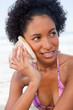 Photo: Woman looking towards the side while listening to the sound of the sea in a shell Woman looking towards the side while listening to the sound of the sea in a shell