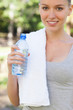 Smiling athletic woman with a bottle of water in the park