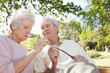 Woman closely smells a flower which is being held by her friend