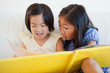 One sister turning the page as the other still reads