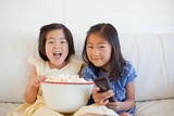 Photo: Two sisters on the couch with a bowl of popcorn and the tv remote while laughing Two sisters on the couch with a bowl of popcorn and the tv remote while laughing