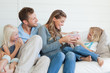 A happy family sit on the couch as the son hands his mother a present