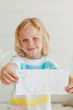 A small boy smiling as he holds a letter to santa