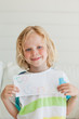 A smiling boy holds his letter to santa close to himself