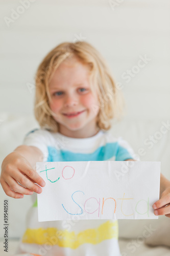 Photo: A small boy smiling as he holds a letter to santa A small boy smiling as he holds a letter to santa