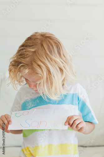 Photo: A young boy looking at his letter to santa A young boy looking at his letter to santa