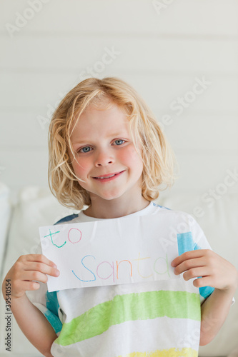 Photo: A smiling boy holds his letter to santa close to himself A smiling boy holds his letter to santa close to himself