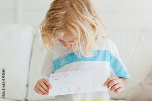 Photo: A small boy looks at the letter to santa in his hands A small boy looks at the letter to santa in his hands