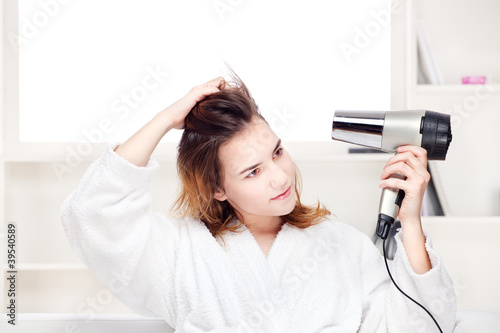 Photo: girl drying her hair at home girl drying her hair at home