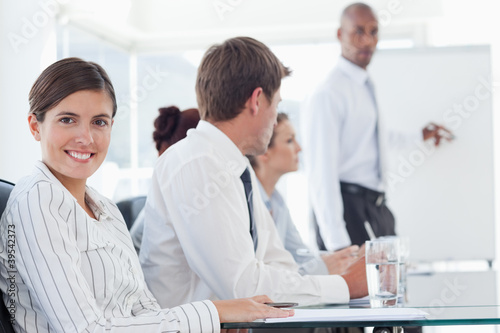 Photo: Smiling saleswoman with presentation being held behind her Smiling saleswoman with presentation being held behind her