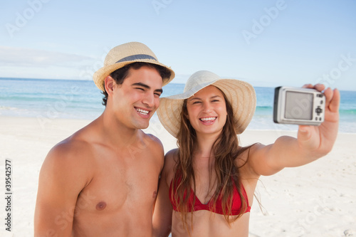 Photo: Smiling couple in swimsuit taking a picture together Smiling couple in swimsuit taking a picture together