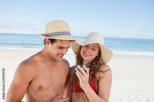 Photo: Close-up of a couple in swimsuit checking their picture Close-up of a couple in swimsuit checking their picture