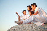 Photo: Family sitting on a natural stone wall together as the son points in front of him Family sitting on a natural stone wall together as the son points in front of him