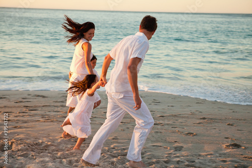 Photo: Family holding hands as they walk on the beach Family holding hands as they walk on the beach
