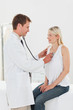Smiling doctor taking his patients heart beat